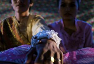 Wedding guests tie white string, often with money attached, to signify prayers and prosperity for the couple in their new life together.
