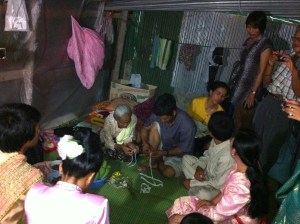 The family of the bride and groom, praying for them.  Wedding guests tie white string (often with money) to the couple's wrists as a sign of well wishes and prosperity in their new life together.